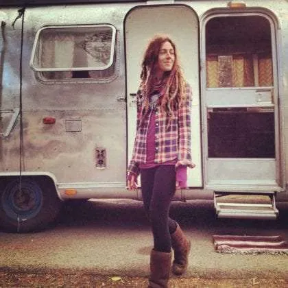 a fabulously beautiful woman stands in front of a vintage airstream