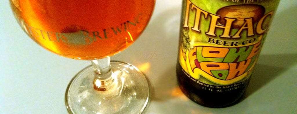 a glass of beer next to an Ithaca Brewing Company Flower Power IPA bottle