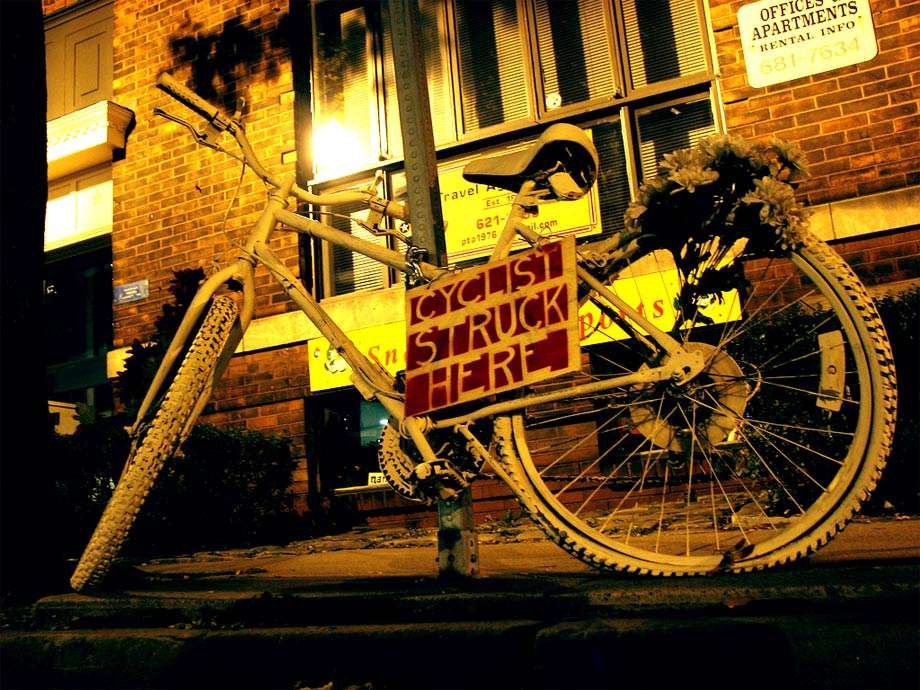 a bicycle painted white with a sign that reads Cyclist Struck Here, its a ghost bike, commemorating a bicycle rider who died on this spot