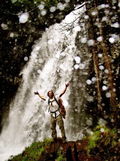 waterfall a backpacker stands at the foot of a waterfall, the camera lens is covered in water droplets
