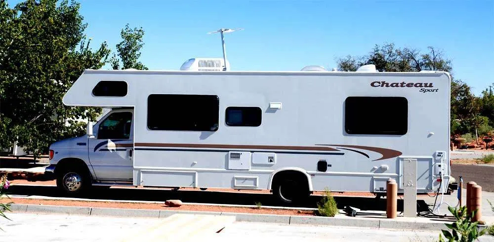 class c rv parked at an RV park with hookups