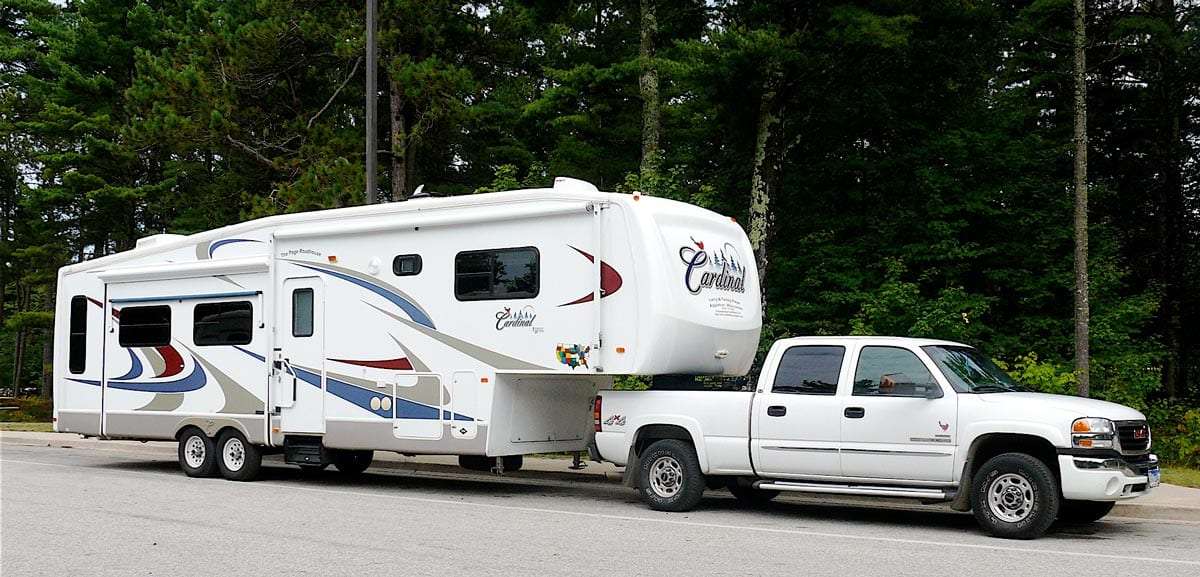 a large white trailer is attached to the bed of a pickup truck