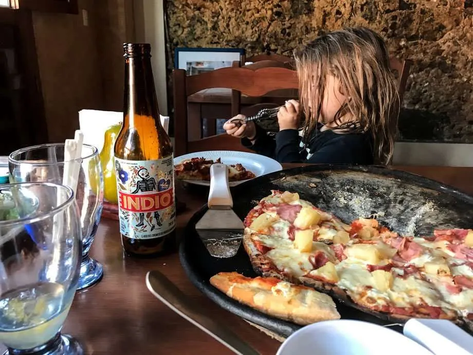 A boy playing with a wine opener at a pizza place