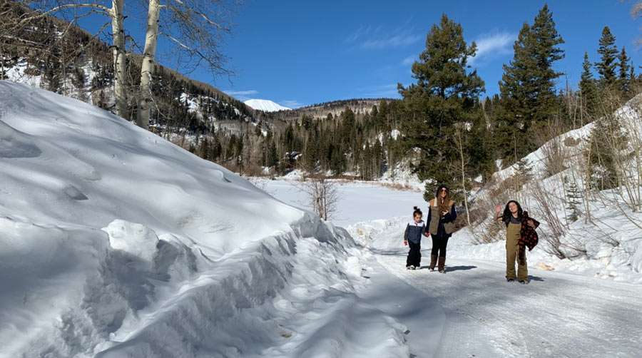 a family walks up a snowy hill on a sunny day