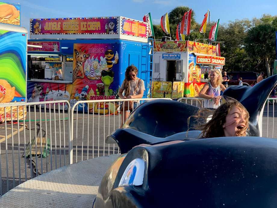 a child enjoys a ride at a carnival while two women laugh