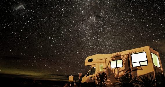 an rv parked beneath a starry sky in a national park