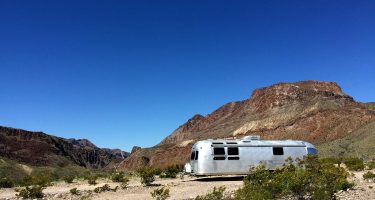 a vintage 1976 airstream travel trailer at big bend ranch state park, surrounded by blue skies and big mountains